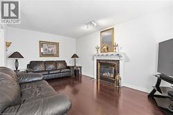 Living area with dark wood-type flooring, track lighting, and a fireplace - 
