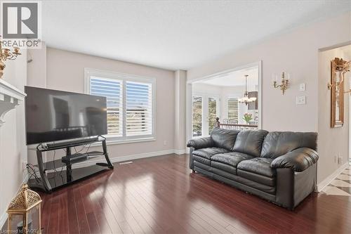 Living area with dark wood-style flooring, suspended lighting, and a textured ceiling - 54 Woodcrest Court, Kitchener, ON - Indoor Photo Showing Living Room