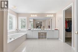 Bathroom featuring double vanity, a walk in closet, a bath, and light tile patterned floors - 