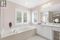 Bathroom featuring vanity, light tile patterned floors, and a bath - 