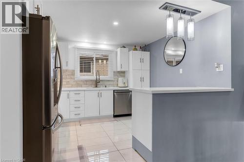 Kitchen featuring white cabinetry, stainless steel appliances, decorative backsplash, and pendant lighting - 51 Independence Drive, Hamilton, ON - Indoor Photo Showing Kitchen