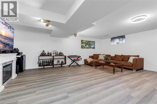 Living room featuring a textured ceiling, light wood finished floors, and a high end fireplace - 51 Independence Drive, Hamilton, ON - Indoor With Fireplace