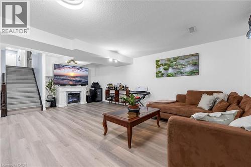 Living area with light wood-type flooring, a glass covered fireplace, and a textured ceiling - 51 Independence Drive, Hamilton, ON - Indoor Photo Showing Living Room With Fireplace