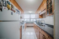 Kitchen featuring glass insert cabinets, white appliances, a textured ceiling, backsplash, and light tile patterned floors - 