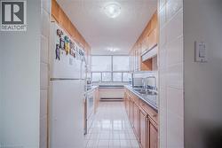 Kitchen featuring white appliances, a textured ceiling, light tile patterned floors, light countertops, and a baseboard heating unit - 
