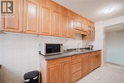 Kitchen with dark countertops, glass insert cabinets, stainless steel microwave, a textured ceiling, and light tile patterned flooring - 