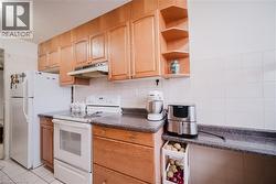 Kitchen with white electric range, dark countertops, open shelves, decorative backsplash, and a textured ceiling - 