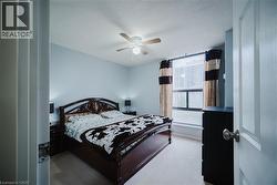 Bedroom featuring a ceiling fan, a textured ceiling, and light colored carpet - 