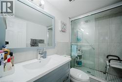 Full bath featuring vanity, a stall shower, and tile walls - 