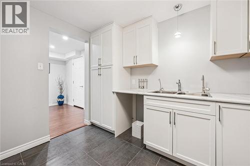 Kitchen featuring light countertops, dark tile patterned floors, white cabinets, and hanging light fixtures - 488 Heather Hill Place, Waterloo, ON - Indoor Photo Showing Kitchen With Double Sink