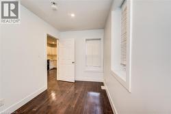 Main floor secondary bedroom featuring dark wood finished floors - 