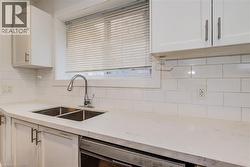 Kitchen featuring white cabinetry, stainless steel dishwasher, quartz counters, and tasteful backsplash - 