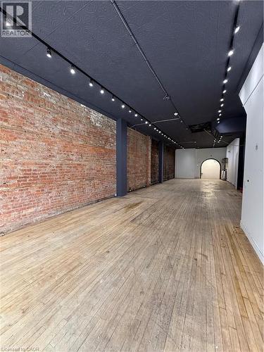 Retail Space featuring rail lighting and brick wall - 228 James Street N, Hamilton, ON 