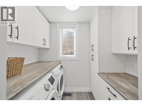 Laundry room off of the kitchen with storage and counter space - 1860 Blue Bunch Court, Kelowna, BC - Indoor Photo Showing Laundry Room