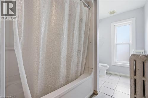 Full bathroom featuring shower / bath combo with shower curtain and light tile patterned floors - 30 Regina Street N, Waterloo, ON 