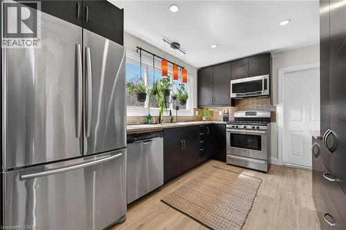 Kitchen with stainless steel appliances, light wood-style floors, light stone countertops, backsplash, and modern cabinets - 844 Upper Wellington Street, Hamilton, ON - Indoor Photo Showing Kitchen