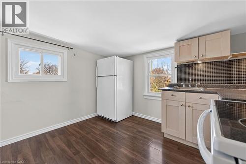 Kitchen featuring white appliances, dark countertops, decorative backsplash, dark wood-style flooring, and light wood finish cabinets - 844 Upper Wellington Street, Hamilton, ON - Indoor Photo Showing Laundry Room