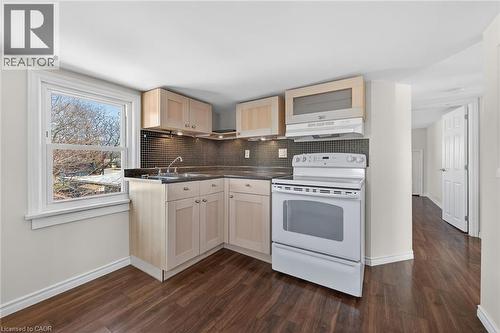 Kitchen with white range with electric stovetop, dark countertops, dark wood-type flooring, tasteful backsplash, and light wood finish cabinets - 844 Upper Wellington Street, Hamilton, ON - Indoor Photo Showing Kitchen