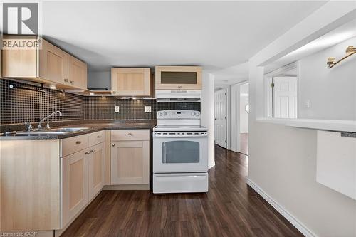 Kitchen featuring light wood finish cabinets, white electric range oven, dark wood-style flooring, and backsplash - 844 Upper Wellington Street, Hamilton, ON - Indoor Photo Showing Kitchen