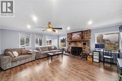 Living room with ceiling fan, wood finished floors, a desk, and crown molding - 