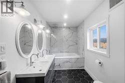 Full bathroom with double vanity, a tub with marble appearance, dark tile patterned floors, and a marble finish shower - 