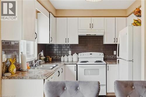 Kitchen with white appliances, white cabinets, light countertops, and decorative backsplash - 750 Lawrence Street Unit# 88, Cambridge, ON - Indoor Photo Showing Kitchen With Double Sink