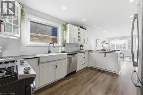 Kitchen featuring glass insert cabinets, a peninsula, stainless steel appliances, white cabinets, and dark wood finished floors - 171 Glencairn Avenue, Hamilton, ON - Indoor Photo Showing Kitchen With Upgraded Kitchen