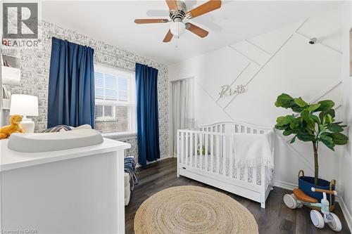 Bedroom featuring a crib, dark wood finished floors, ceiling fan, and wallpapered walls - 171 Glencairn Avenue, Hamilton, ON - Indoor Photo Showing Bedroom