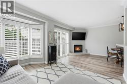 Living room with light wood finished floors, ornamental molding, and a glass covered fireplace - 