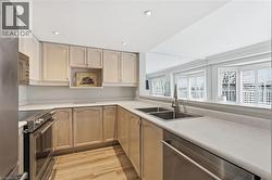 Kitchen featuring stainless steel appliances, light wood finish cabinets, light wood-type flooring, light countertops, and recessed lighting - 