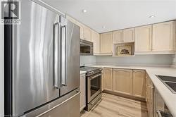 Kitchen with stainless steel appliances, light wood finish cabinetry, light countertops, light wood-type flooring, and recessed lighting - 