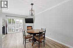 Dining space featuring a glass covered fireplace, ornamental molding, and light wood finished floors - 