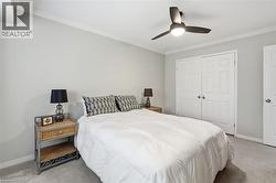 Bedroom with light carpet, ornamental molding, a ceiling fan, and a closet - 