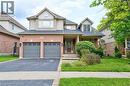 View of front of house featuring an attached garage, a porch, driveway, a front yard, and brick siding - 2215 Tiger Road, Burlington, ON  - Outdoor With Facade 