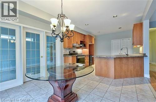 Kitchen featuring wood finish cabinets, electric stove, a peninsula, and light tile patterned floors - 2215 Tiger Road, Burlington, ON - Indoor Photo Showing Dining Room