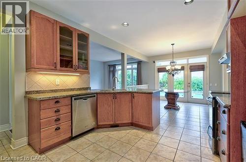 Kitchen featuring glass fronted cabinets, a peninsula, stainless steel appliances, and dark stone countertops - 2215 Tiger Road, Burlington, ON - Indoor Photo Showing Kitchen
