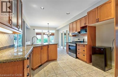 Kitchen featuring backsplash, stainless steel appliances, wood finish cabinets, a peninsula, and dark stone countertops - 2215 Tiger Road, Burlington, ON - Indoor Photo Showing Kitchen