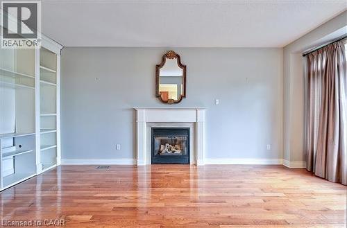 Unfurnished living room featuring built in shelves, light wood-style flooring, and a glass covered fireplace - 2215 Tiger Road, Burlington, ON - Indoor Photo Showing Living Room With Fireplace