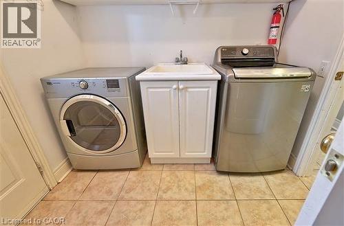 Laundry area with washing machine and dryer, cabinet space, and light tile patterned floors - 2215 Tiger Road, Burlington, ON - Indoor Photo Showing Laundry Room