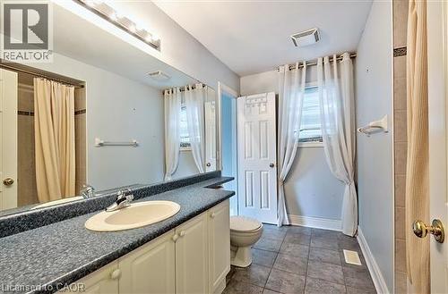 Bathroom featuring curtained shower, vanity, healthy amount of natural light, and dark tile patterned floors - 2215 Tiger Road, Burlington, ON - Indoor Photo Showing Bathroom