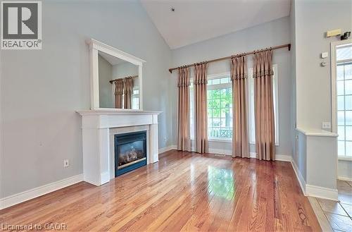 Unfurnished living room featuring light wood-type flooring, lofted ceiling, and a glass covered fireplace - 2215 Tiger Road, Burlington, ON - Indoor With Fireplace