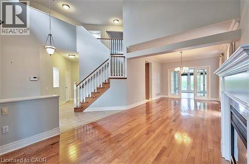 Unfurnished living room with light wood finished floors, a chandelier, a high ceiling, and a fireplace - 2215 Tiger Road, Burlington, ON - Indoor Photo Showing Other Room