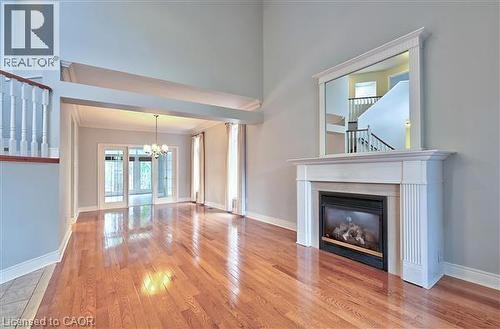 Unfurnished living room with light wood-style flooring, a glass covered fireplace, suspended lighting, and ornamental molding - 2215 Tiger Road, Burlington, ON - Indoor Photo Showing Living Room With Fireplace