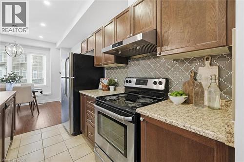Wood cabinetry and patterned tile backsplash. - 122 E Dundas Street E Unit# 9, Waterdown, ON - Indoor Photo Showing Kitchen