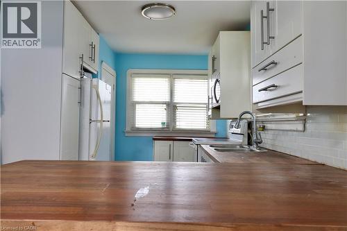 Kitchen with wooden counters, white cabinets, freestanding refrigerator, range with electric stovetop, and stainless steel microwave - 80 Roseview Avenue, Cambridge, ON - Indoor Photo Showing Kitchen With Double Sink
