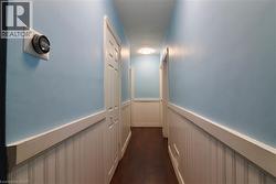 Corridor featuring a wainscoted wall and dark wood-style floors - 
