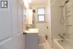 Bathroom with vanity, shower / bath combination, and light marble finish flooring - 
