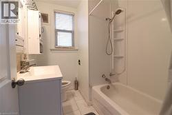 Full bathroom featuring vanity, shower / tub combo with curtain, and light marble finish floors - 