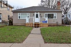 Bungalow featuring roof with shingles and a wooden deck - 