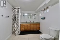 Bathroom with double vanity, a shower with curtain, and dark tile patterned floors - 